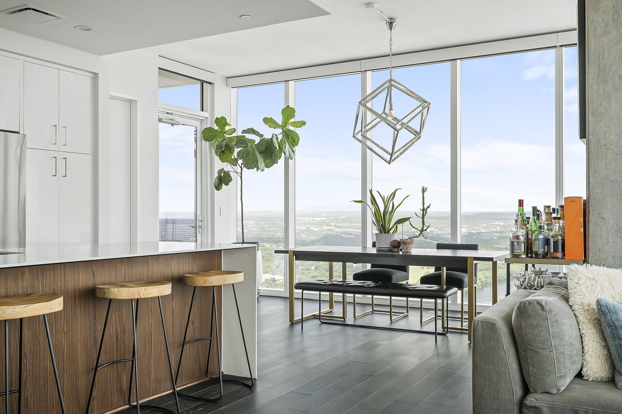 Kitchen and dining area in a condo sold by Leila Showery, with floor-to-ceiling windows, wood bar stools and city views.